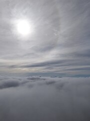 Obraz premium Serene aerial skyscape. Drone image at dawn above the clouds. Aerial view above a dense sea of clouds, with soft sunlight and a subtle halo in the sky.