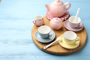 Beautiful ceramic tea set for children on light blue wooden table, closeup. Space for text