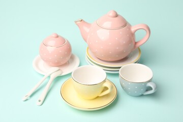 Beautiful ceramic tea set for children on turquoise background, closeup