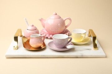 Tray with beautiful ceramic tea set for children on beige background