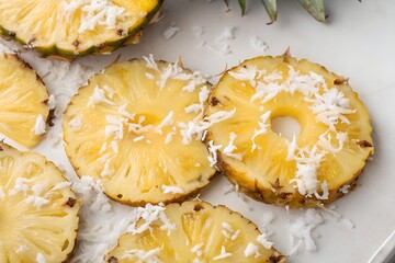 Pineapple. Close-up of fresh pineapple slices topped with grated coconut, arranged on a white plate