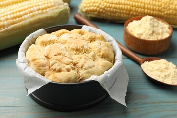 Freshly baked cornbread, flour and cobs on light blue wooden table, closeup