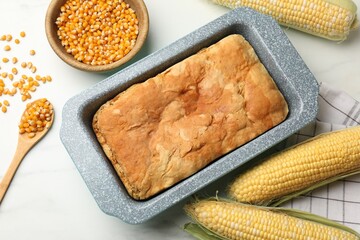 Freshly baked cornbread, seeds and cobs on white marble table, flat lay