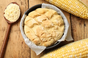 Freshly baked cornbread, flour and cobs on wooden table, flat lay