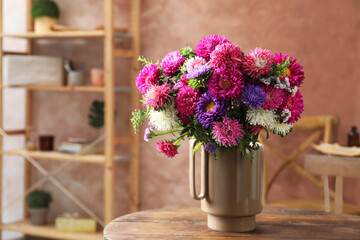 Beautiful flowers in vase on wooden table indoors. Space for text
