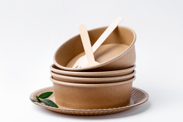 Set of disposable tableware and green leaves on white background, closeup