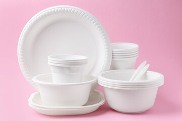 Set of disposable plastic tableware on pink background, closeup