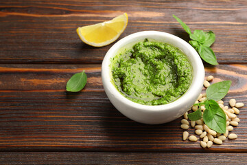 Fresh pesto sauce and ingredients on wooden table, closeup. Space for text