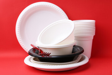 Set of disposable plastic tableware on red background, closeup