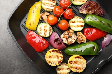 Pan with grilled vegetables and spices on grey table, top view
