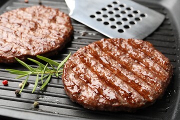 Pan with grilled patties, spices and slotted spatula, closeup