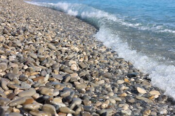 Beautiful view of wavy sea and pebbles on beach, closeup