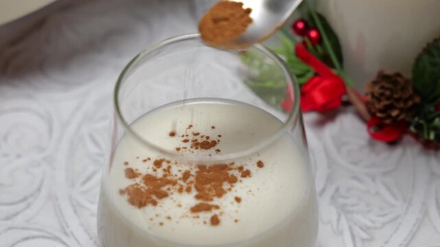 Sprinkling cinnamon powder on christmas eggnog rompope