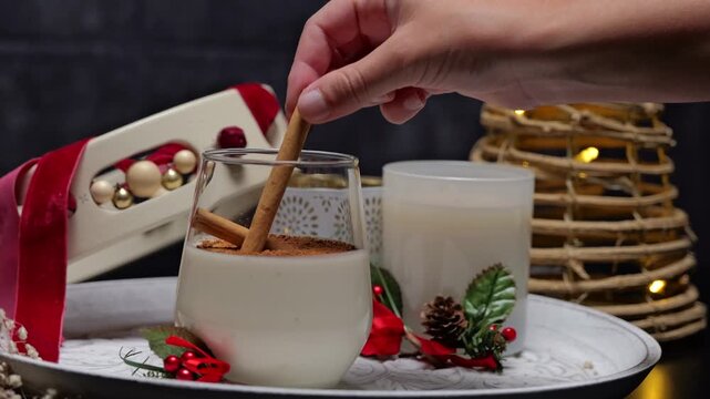 Hand stirring christmas rompope with cinnamon stick