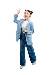 Full body Asian Woman cheerfully waving while holding a phone. She wears a blue blazer and jeans,...