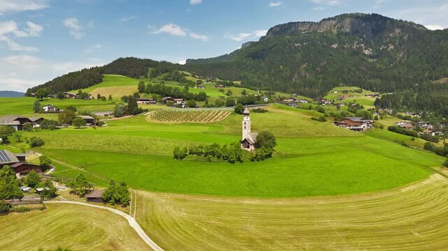 Chiesa di San Valentino framed by meadows, aerial view. Summer countryside context in northern Italy