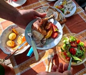 Meat and vegetables. One person holds a plate with roasted chicken and vegetables in their hands.