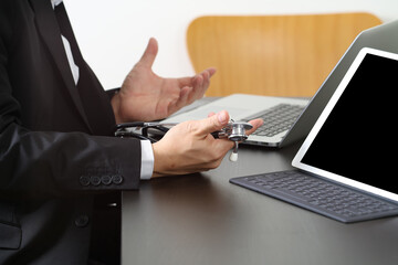 Doctor working with laptop and stethoscope in office