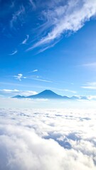 High-altitude view of a mountain above a sea of clouds, vibrant blue sky