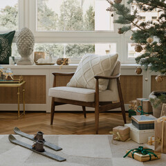 Mid-century armchair with knitted cushion beside gifts and a simple vintage wooden skis add nostalgic charm to the cozy Christmas setting.