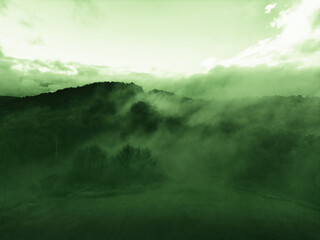 Monochrome rendering of a drone arial shot with fog over a mountain landscape. Ideal for backgrounds