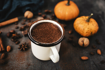 Mug of hot chocolate, pumpkins and spices on rustic background, cozy autumn scene