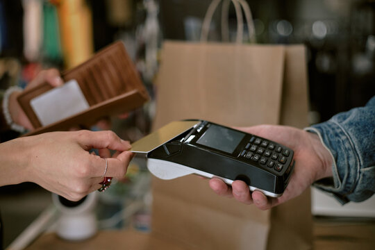Credit card payment at store checkout with shopping bag in hand