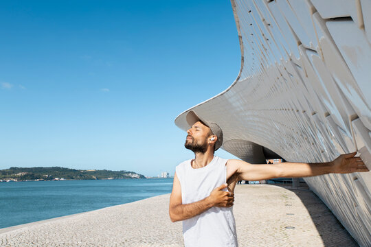 Runner stretching by MAAT museum in Lisbon on a summer morning