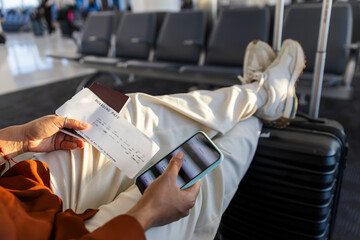 Close-up of hands holding boarding pass and smartphone at airport terminal