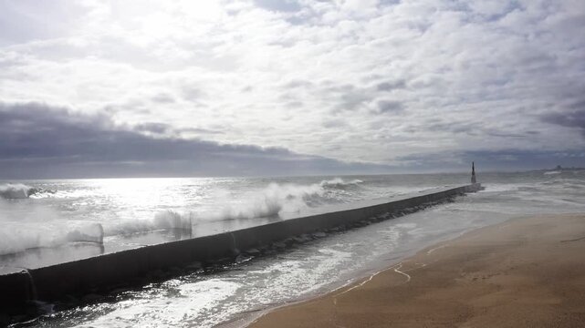 Huge waves crashing over Breakwater during winter storm Atlantic waves washing the lighthouse on Praia da Aguda sandy beach at Aguda settlement near Porto, Portugal. Incredible 4K flying drone video.