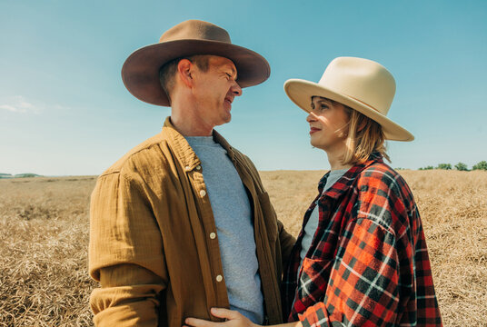 Couple in cowboy hats sharing quiet romantic moment in sunlit field