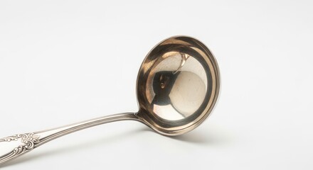 A close-up studio shot of a silver ladle with an ornate handle against a white background.