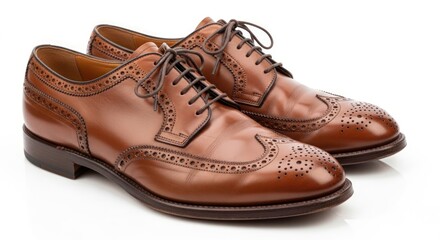 A pair of classic brown leather wingtip brogue dress shoes with laces, presented on a white background.
