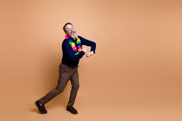 Cheerful middle-aged man wearing a lei expresses joy and energy against a beige studio background