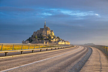 Morning light over Mont Saint-Michel, viewed from the modern bridge leading to the historic island, blending medieval architecture with a scenic approach