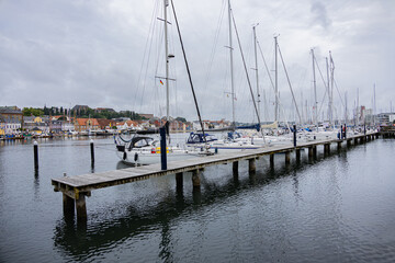 Fototapeta premium Wooden pier with moored yachts and colorful waterfront houses in Flensburg harbor