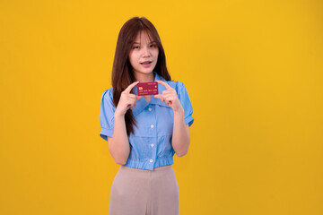 A stylish young woman in a light blue blouse holds a credit card, smiling thoughtfully