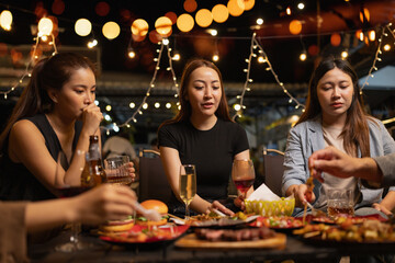 Happy Friends Celebrating Together at Night, Young Asian Group of Friends Having Fun and Toasting Drinks Outdoors At Night, Enjoying a Celebration Concept.