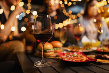 Happy Friends Celebrating Together at Night, A glass of red wine on table.