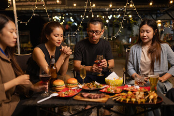 Happy Friends Celebrating Together at Night, Young Asian Group of Friends Having Fun and Toasting Drinks Outdoors At Night, Enjoying a Celebration Concept.
