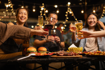 Happy Friends Celebrating Together at Night, Young Asian Group of Friends Having Fun and Toasting Drinks Outdoors At Night, Enjoying a Celebration Concept.