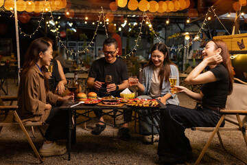 Happy Friends Celebrating Together at Night, Young Asian Group of Friends Having Fun and Toasting Drinks Outdoors At Night, Enjoying a Celebration Concept.