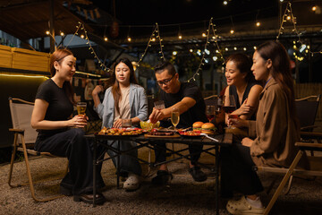 Happy Friends Celebrating Together at Night, Young Asian Group of Friends Having Fun and Toasting Drinks Outdoors At Night, Enjoying a Celebration Concept.