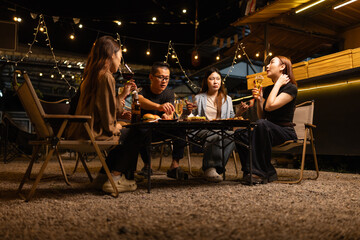 Happy Friends Celebrating Together at Night, Young Asian Group of Friends Having Fun and Toasting Drinks Outdoors At Night, Enjoying a Celebration Concept.