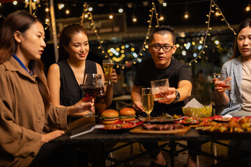 Happy Friends Celebrating Together at Night, Young Asian Group of Friends Having Fun and Toasting Drinks Outdoors At Night, Enjoying a Celebration Concept.