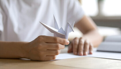 Origami Crafting: A person's hands delicately hold a white origami crane, demonstrating the art of paper folding with patience and precision. 