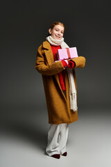 Stylish preteen girl poses warmly with gifts in trendy winter outfit
