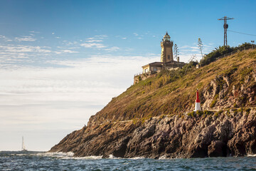 Aviles coastal lighthouse perched on a Rocky Hillside under a Blue Sky
