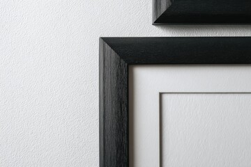 Close-up of two black picture frames on a textured wall