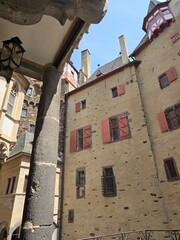 Medieval castle courtyard with red shutters and stone columns under blue sky